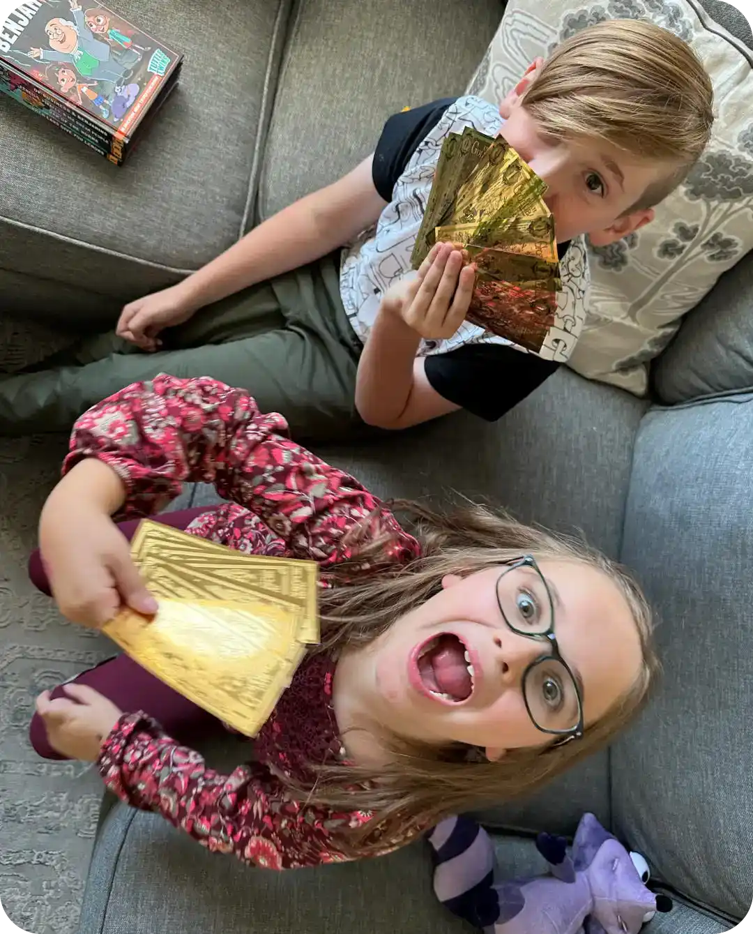 Two people playfully biting into golden chocolate bars while lounging on a couch.